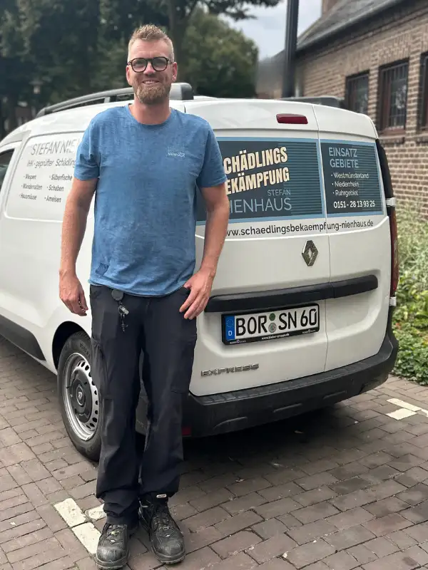 Kammerjäger Stefan Nienhaus neben seinem Firmenwagen für Schädlingsbekämpfung in Wesel mit Logo und Kontaktdaten.