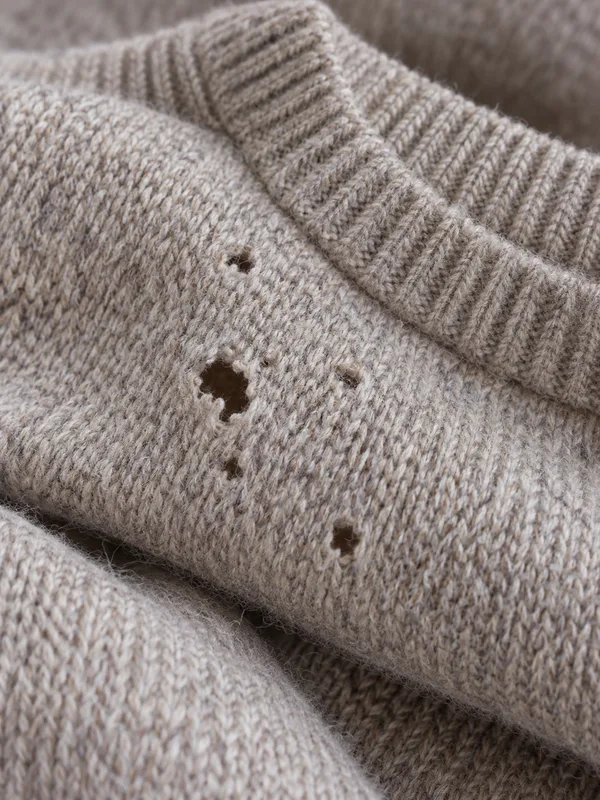 Fraßlöcher von Kleidermotten in einem Wollpullover